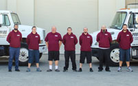 The Poulos Moving Sytems team standing in front of our trucks and warehouse.