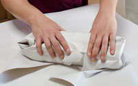 Close up of hands wrapping an object for packing into a box.